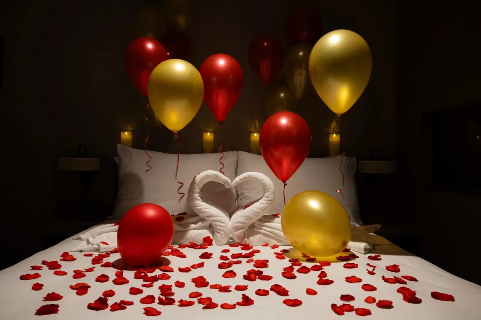 Hotel room decorated with balloons and rose petals
